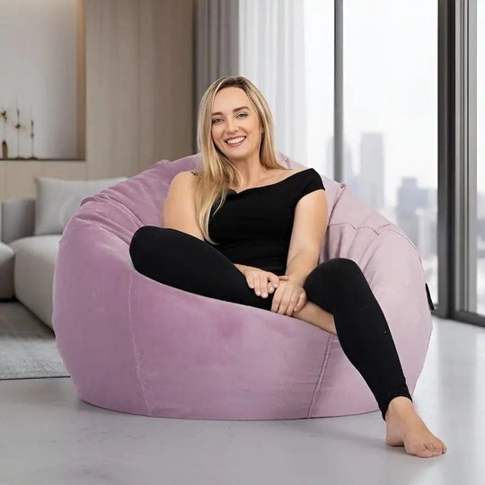 Woman sitting on a large pink bean bag chair in a modern living room.