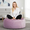 Woman sitting on a purple bean bag in a modern living room.