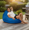 Man relaxing on a blue bean bag chair outdoors on a wooden deck.