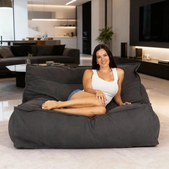 Woman sitting on a large gray bean bag in a modern living room.