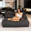 Woman sitting on a large gray bean bag in a modern living room.
