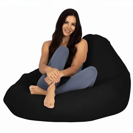 Woman sitting on a black bean bag chair against a white background