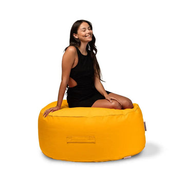 Woman sitting on a yellow bean bag chair against a white background