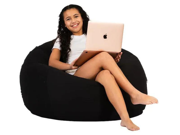 Woman sitting on a black bean bag with a laptop on a white background