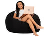 Woman sitting on a black bean bag with a laptop on a white background
