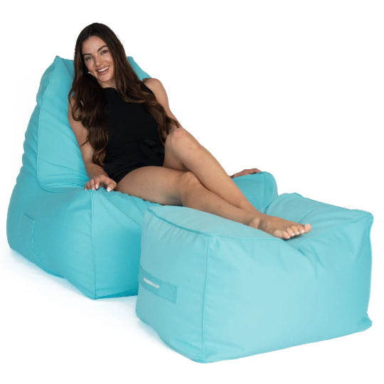 Woman sitting on a capri blue Copacabana bean bag chair with ottoman on a white background