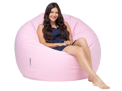 Woman sitting on a pink bean bag chair against a white background