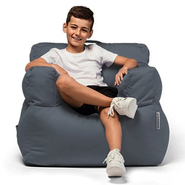 Child sitting on a gray bean bag chair against a white background